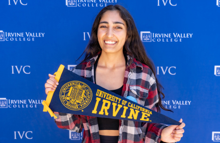 smiling woman holding UC Irvine pennant